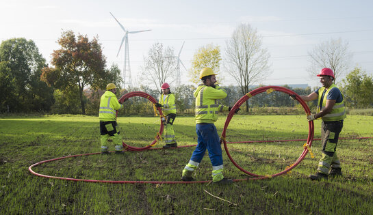 Onze duurzaamheidsstrategie Techniekers rollen kabels af in een veld