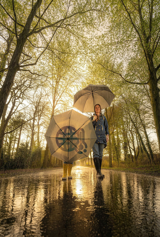 Klimaat en milieu Vrouw en kind wandelen op een nat wegdek met een paraplu